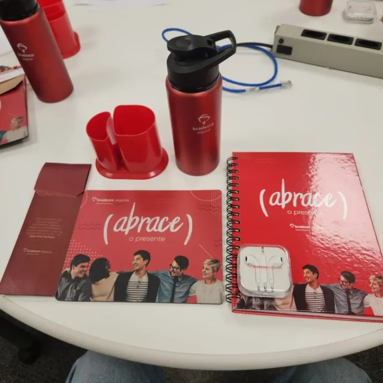 The welcome kit that met me on the first day, laid out on a desk: notebook, bottle and card, all in Bradesco Seguros red.