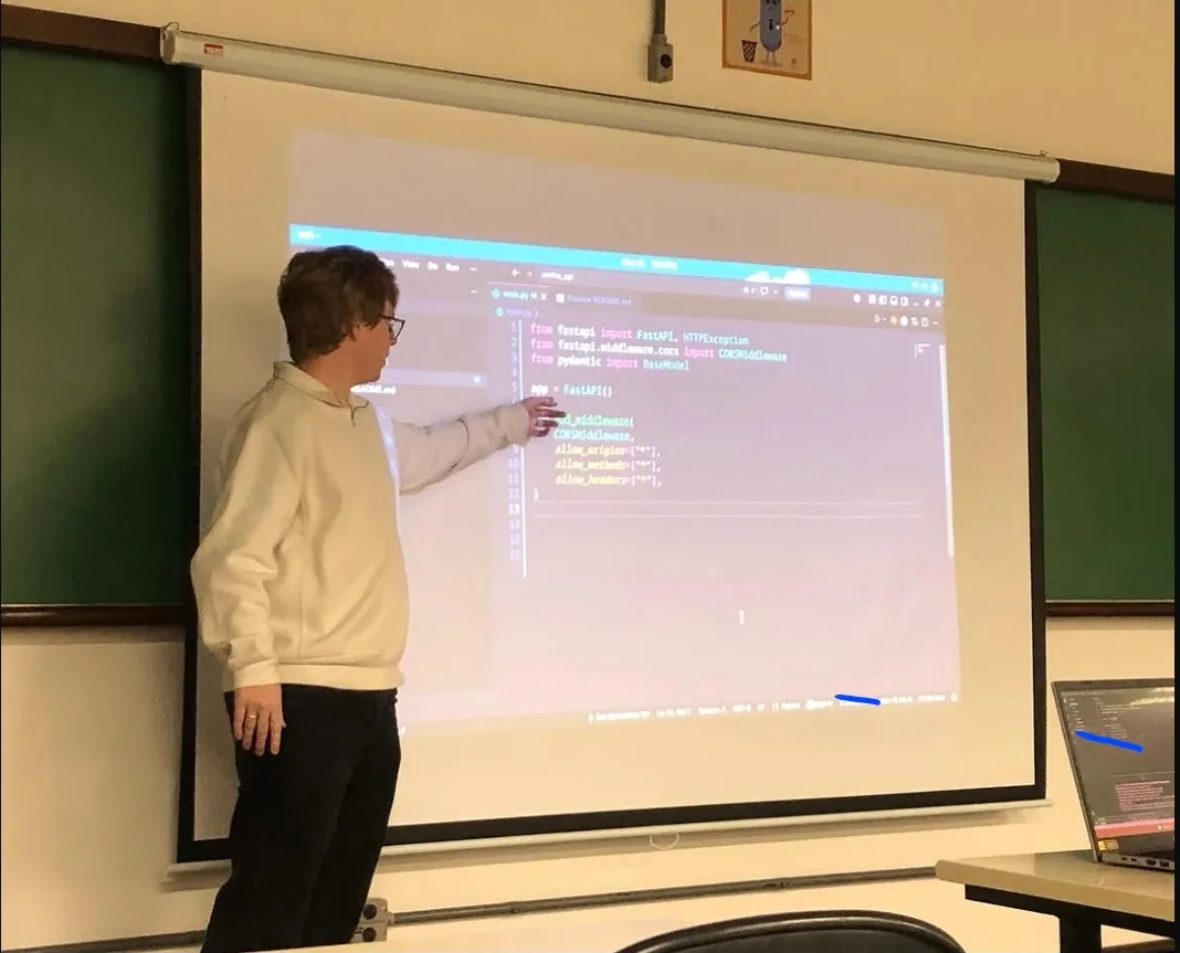 Carlos walking the Builders Club through FastAPI code projected on a classroom screen.