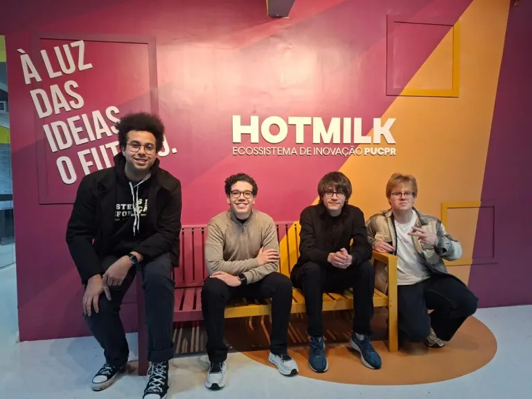 The four of us on a bench in front of the Hotmilk wall at PUCPR, the innovation hub where Nock is being built.